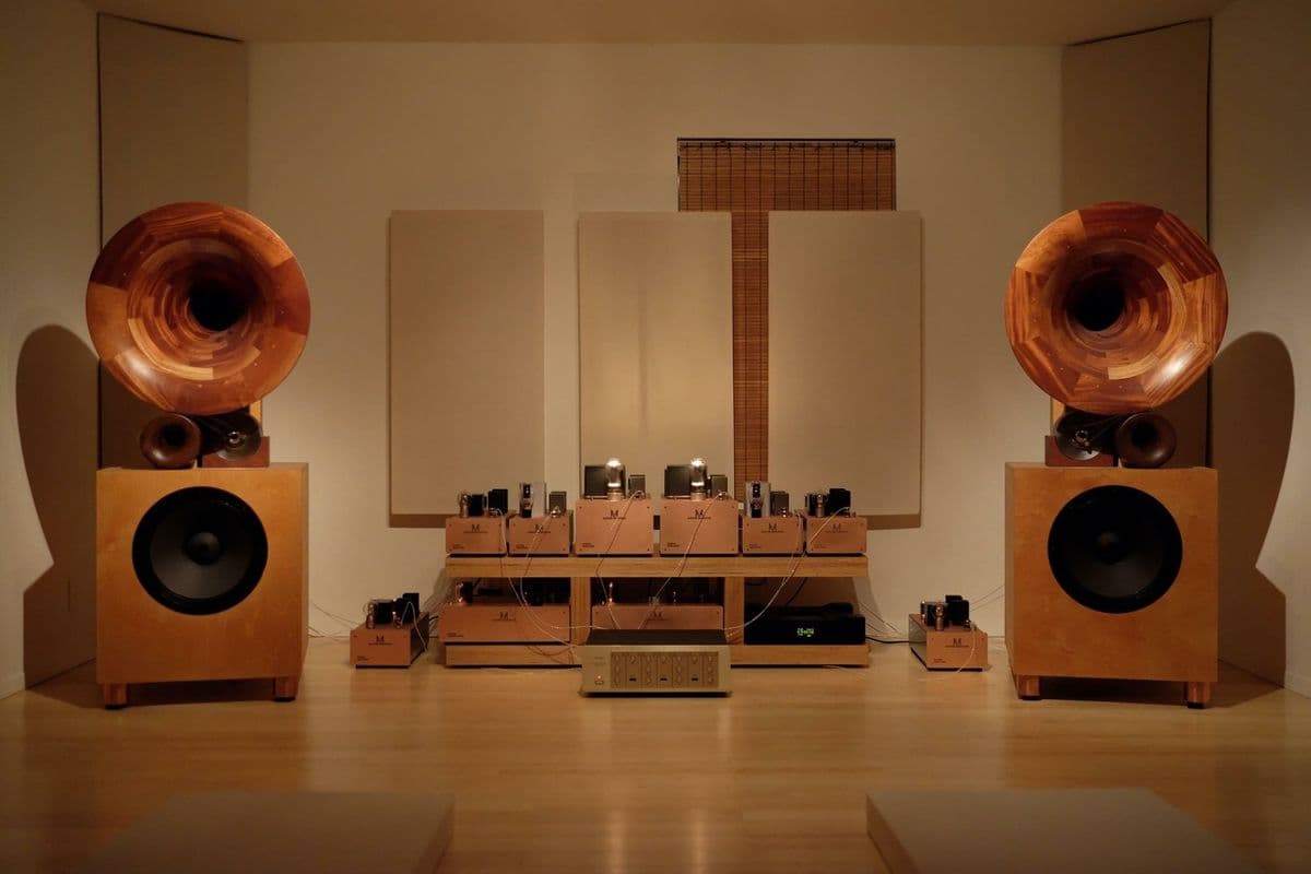 A listening room with two handcrafted wooden horn speakers and glowing tube amplifiers
